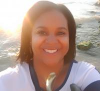 Smiling dark skinned woman with the sun behind her