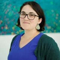Woman with short dark hair, glasses and a blue top