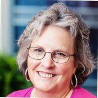 Smiling grey haired woman with glasses and hoop earrings