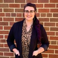 dark haired woman standing in front of a brick building